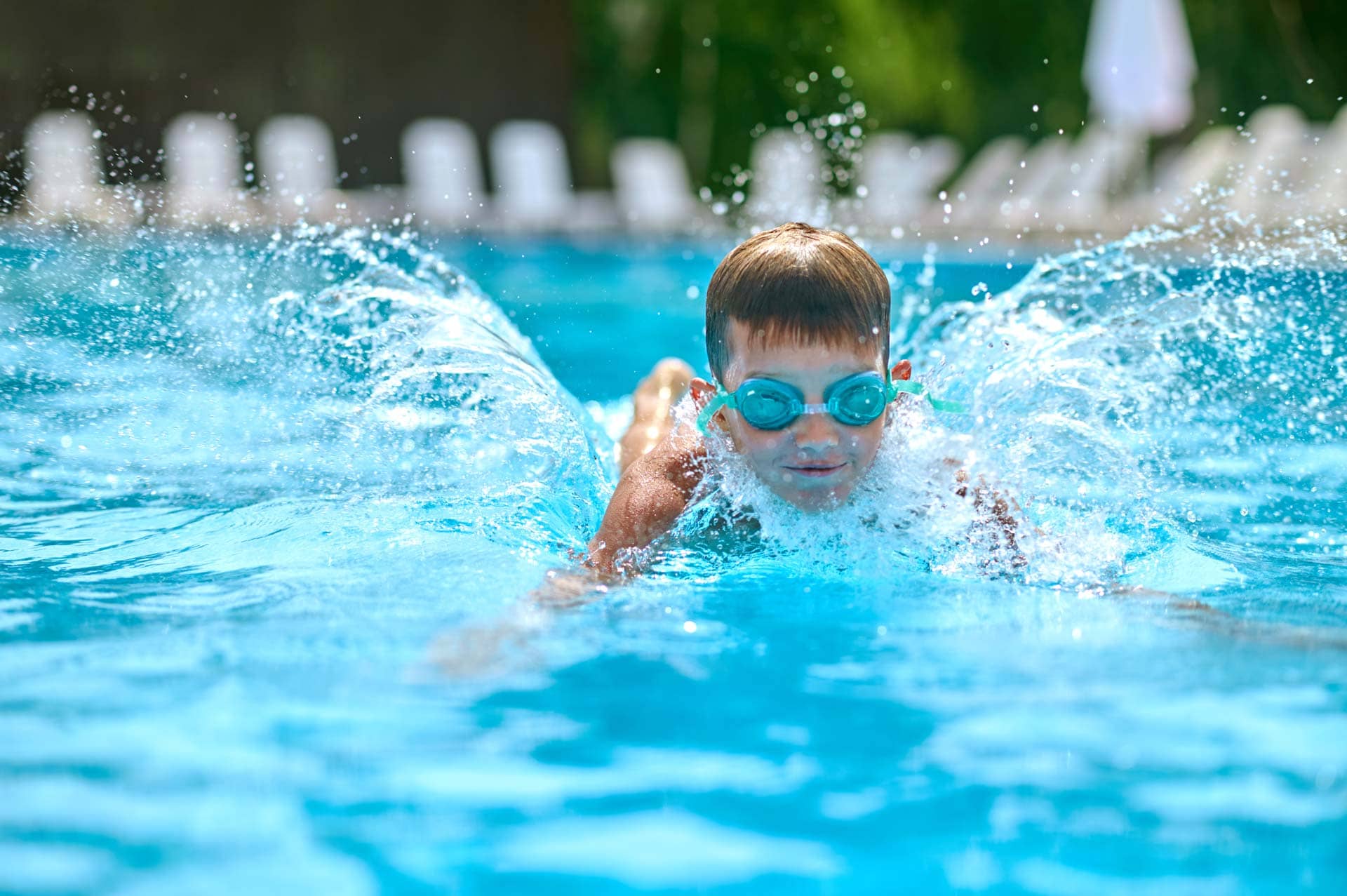 Ein glücklicher Junge mit Taucherbrille der im Pool des Mammendorfer Freibads plantscht