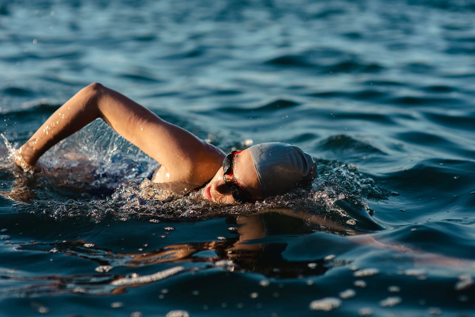 Frau schwimmt sportlich mit Badehaube und Taucherbrille im tiefblauen Badesee Mammendorf